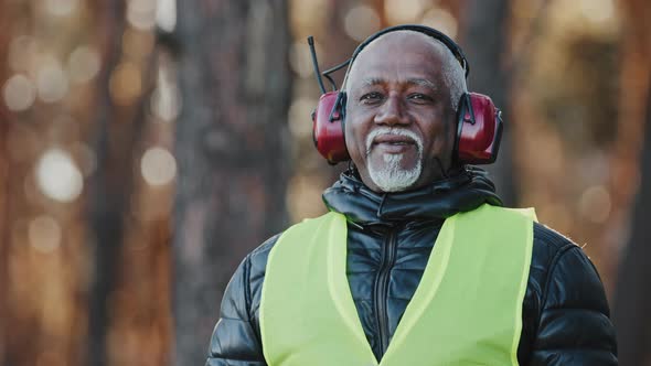 Elderly Man Professional Forestry Engineer in Protective Soundproof Headphones Standing in Forest