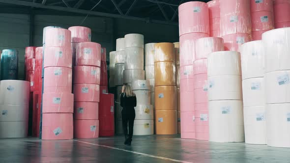 Female Specialist Observing a Storage of Big Paper Rolls