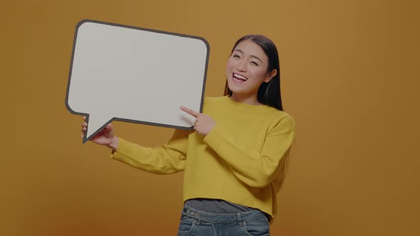 Cheerful Woman Pointing at Empty Speech Bubble in Studio