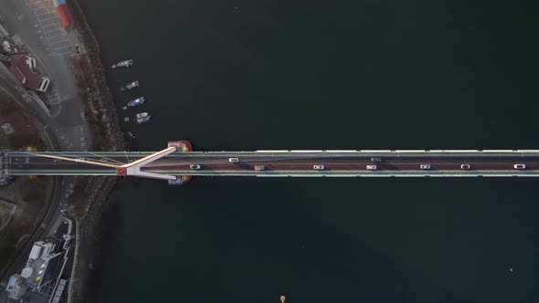 cars come and go through the bridge installed in between a land and an island early in the morning.