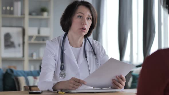 Old Lady Doctor Giving Medical Report to Patient in Clinic