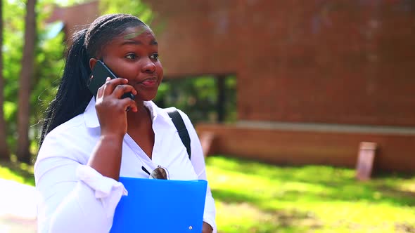 Beautiful Smiling Young African Woman Wearing White Tshirt and Holding a Copybook