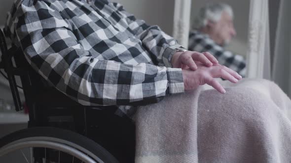 Camera Approaching To Unrecognizable Man's Hands Shaking. Elderly Disabled Man Sitting in Wheelchair