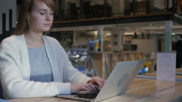 Tired Young Woman Working on Laptop in Cafe