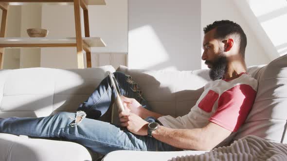 Handsome man using digital tablet while relaxing on the couch