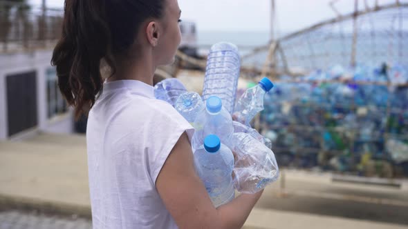 Live Camera Follows Young Caucasian Woman Walking with Collected Trash to Special Place on Sea Coast