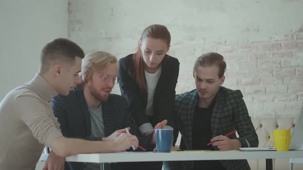 Team of Business People Discuss a Project While Sitting at a Table in the Office. Colleagues Are