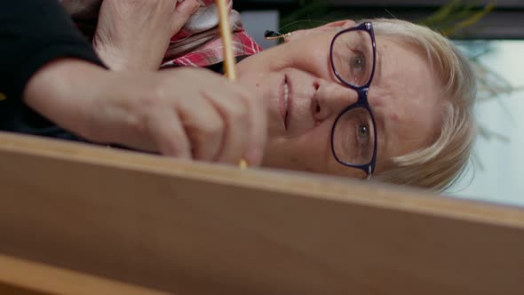 Vertical Video Portrait of Elder Woman Drawing Masterpiece on Canvas alt