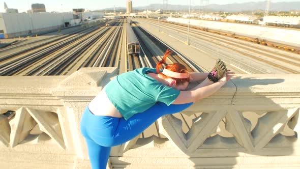 A young woman stretching before working out in urban environment.