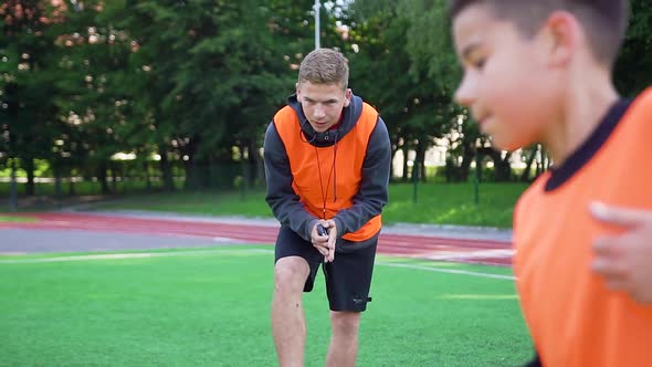 Football Trainer Controling the Time While His Skillful Pupils do Speed Exercises on Outdoors