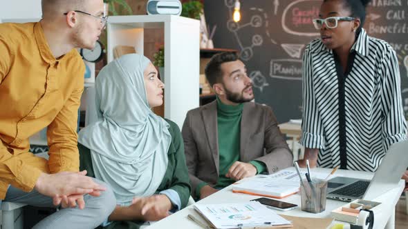 Diverse Group of Businesspeople Talking and Smiling During Informal Meeting in Office