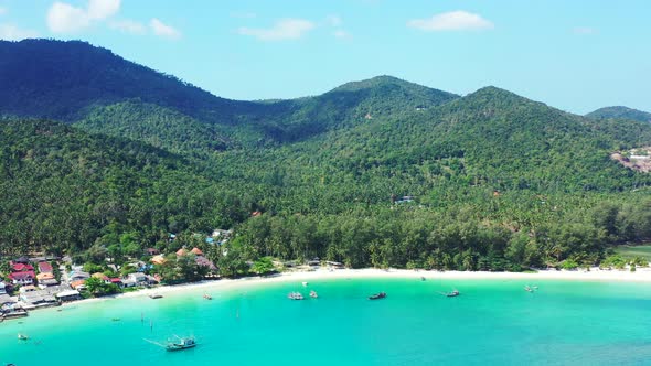 Wide flying tourism shot of a white paradise beach and aqua blue water background