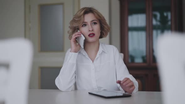 Pretty Business Woman Speaking on Phone and Using Tablet
