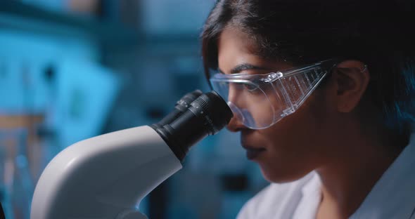 Female Research Scientist Looking Into Microscope,wearing Goggles, Close Up