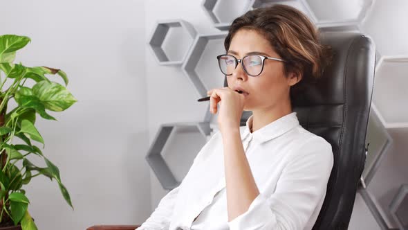 Young Beautiful Businesswoman Thinking Sitting in Armchair at Workplace