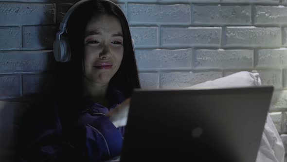 Crying Girl in Headphones Watching Melodramatic Movie on Laptop at Night