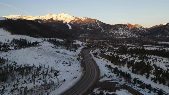 4K drone video of cars driving on road in Rocky Mountains in winter in Colorado.