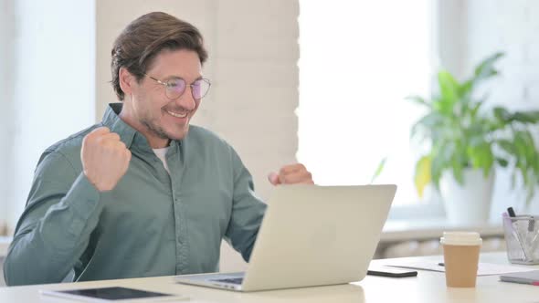 Successful Middle Aged Man Celebrating on Laptop in Office