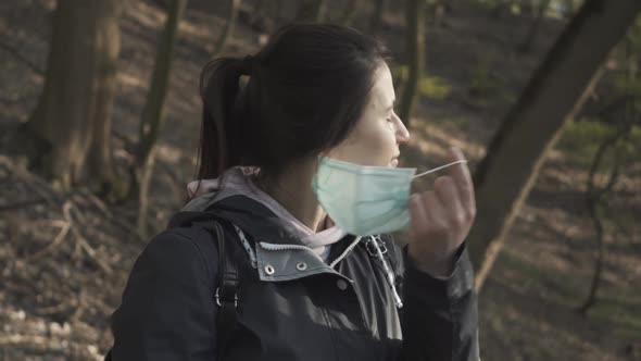 Close-up of Smiling Young Woman Taking Off Face Mask and Inhaling Fresh Air in Spring Park. Happy