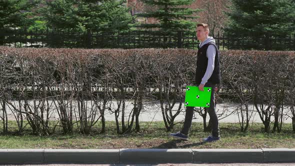 Serious Male Person Walks Near Garden Wall Holding Suitcase, Back Home From Work