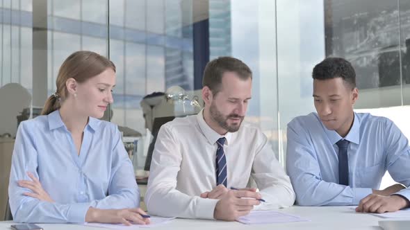 Middle Aged Businessman Having Discussion with His Assistants in Office