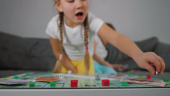 Two Little Girls Playing Table Board Game Rolls Dice and Moves Game Figure