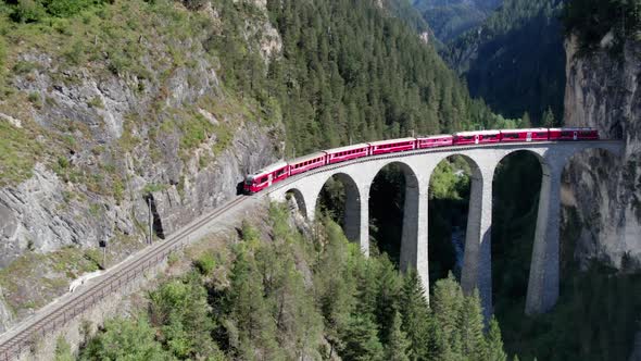 Aerial View of a Moving Red Train Along the Landwasser Viaduct in Swiss Alps