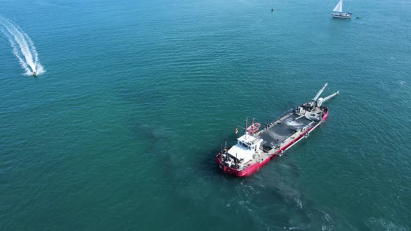 Unique view of a industrial sand dredging vessel disrupting a sensitive marine habitat as it maneuve