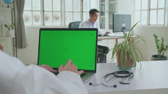 Close Up Asian Woman Doctor Is Using Laptop Computer With Mock Up Green Screen Display In Workplace