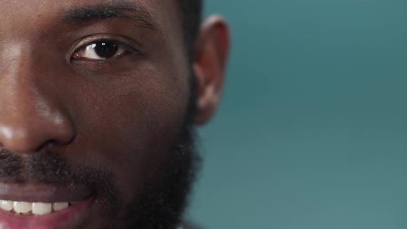 A Young Black Bearded Man in a Official Suit Blinks and Looks at the Camera