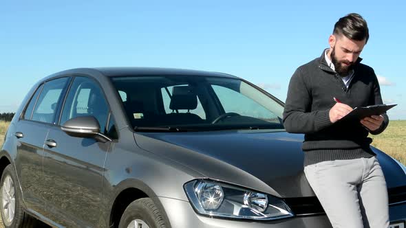 Young Smart Serious Man Describe Condition of Car Behind Him in the Countryside