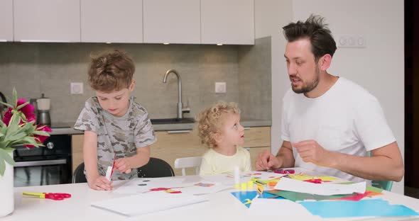 Small Girl and a Small Boy and Their Father are Making Applications with the Coloured Paper and Glue