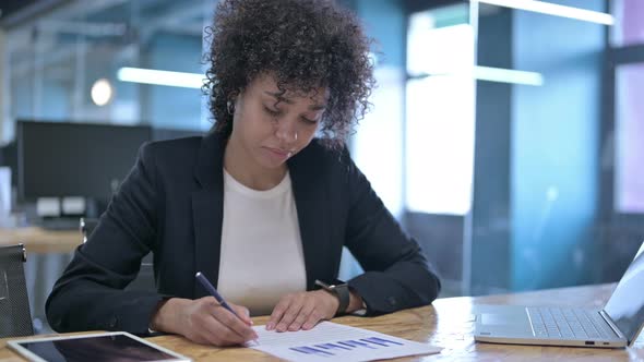 Serious African Businesswoman Writing on Papers While Working in Office