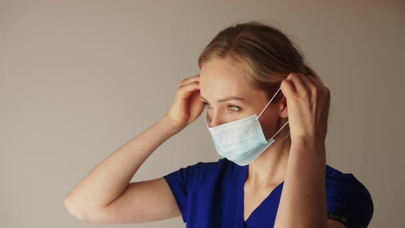 Pretty Blonde Caucasian Nurse Adjusting a Face Mask and Standing Sideways Copy Space Medium Closeup