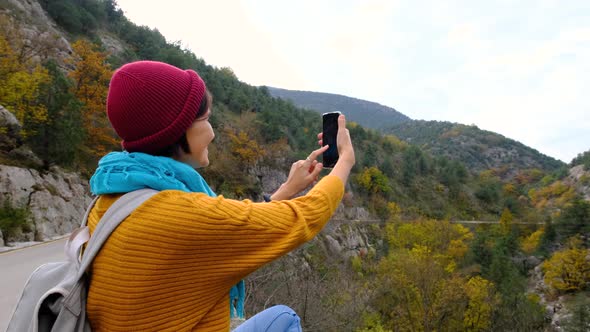 Woman with Backpack Using Smartphone Hiking In The Mountains