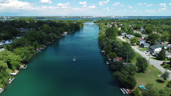 Epic Aerial of riding boat on canadian river during cloudy day with pattern on river surrounded by s