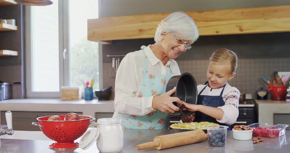 Happy grandmother and granddaughter preparing pie 4k