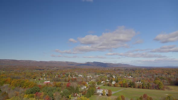 Aerial of autumn trees and huts in farmland, wide shot