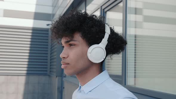 Caucasian Happy Beautiful African American Male in Headphones and Listening to Music Outdoors
