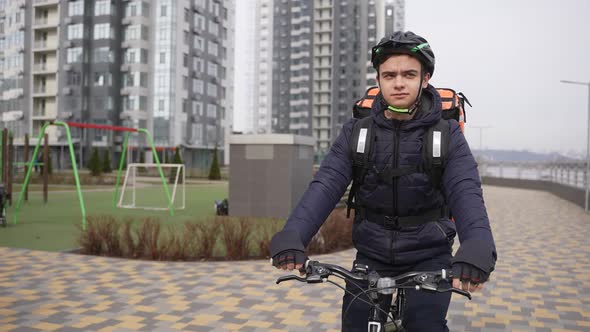 Food Courier Riding Bike Past City Playground