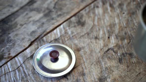 Person put down fresh hot Guayusa Tea on wooden table during travel trip in Amazon Rainforest. Close