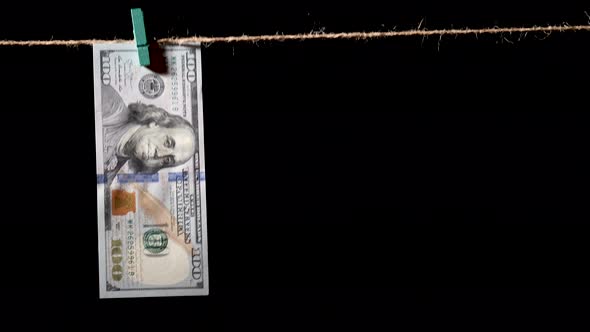 Money laundering concept. AML. Money hanging on a rope on black background. Washed dollars drying