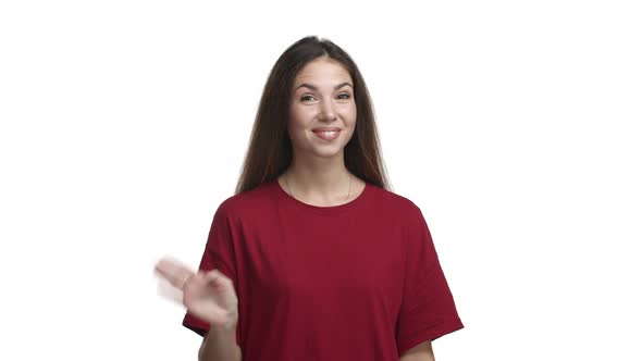 Young Pretty Girl in Red Casual Tshirt Smiling Friendly and Waving at Camera Saying Hello Greeting