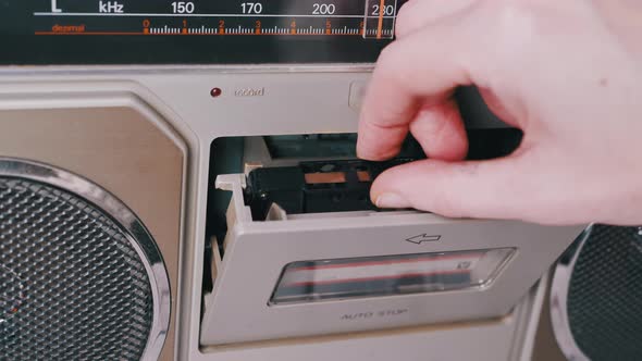 Female Hands Take Out Turn Over an Old Audio Cassette From a Tape Recorder