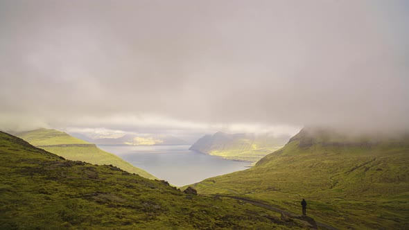 Man Standing Under Clouds Moving Over Fjord