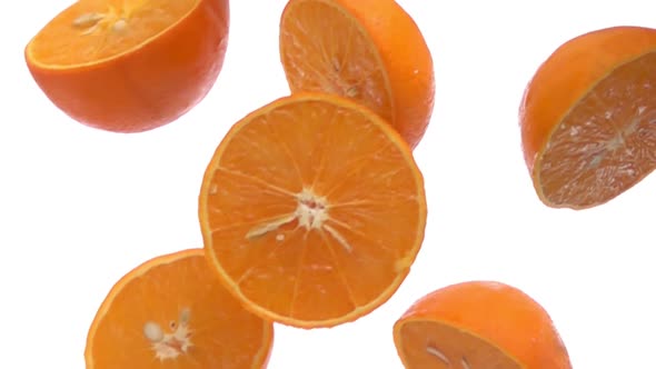 Closeup of the Wet Halves of Orange Falling Diagonally on the White Background