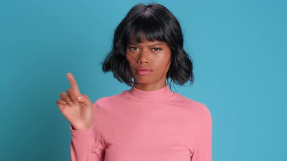 Serious Young Mixed Race Woman Shakes Finger and Says No Against Blue Background