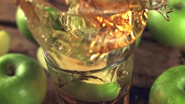 Super Slow Motion with Spray Drops a Piece of Apple Into a Glass of Juice