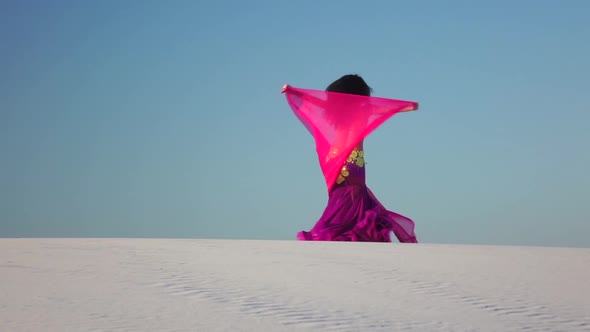 Professional Dancer in the Sandy Desert in the Hands of a Pink Pink Veil. Slow Motion