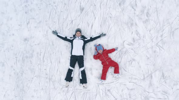 Woman and Kid Lying on Ice in Rink